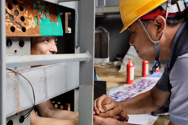 ▲ 2022년 여름, 0.3미터 감옥에 스스로를 가둔 조선하청 노동자 유최안과 만나 악수하는 윤장혁 위원장 ⓒ금속노동자